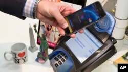 FILE - A customer makes a purchase with a MasterCard using Apple Pay on the iPhone 6 at Walgreens in Times Square in New York, Oct. 20, 2014.