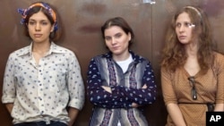 FILE - Pussy Riot members, from left, Nadezhda Tolokonnikova, Yekaterina Samutsevich and Maria Alekhina are seen in a glass cage in a court room during their trial in Moscow last year.