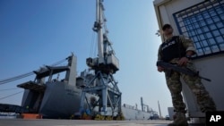 FILE - A Cypriot military police officer stands guards next of the docked U.S. ship carrying Gaza aid, at the port of Larnaca, Cyprus, June 26, 2024.