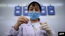 FILE - A technician examines a vile at a laboratory in Shenyang, in China's northeast Liaoning province, June 9, 2020. 