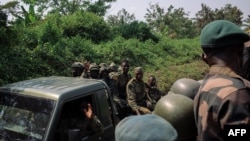 FILE - Soldiers from the Ugandan People's Defence Forces pass soldiers from the 214th DP Battalion of the DRC Armed Forces engaged jointly in Operation Shujaa, on a road between Bulongo and Beni, North Kivu, in the east of the Democratic Republic of Congo, Dec. 17, 2024.