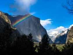 FILE - A rainbow is seen across the Yosemite Valley in front of El Capitan granite rock formation in Yosemite National Park, California, March 29, 2019.