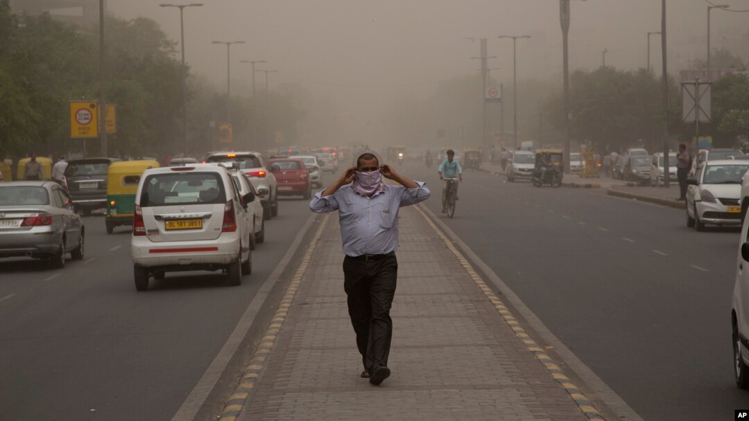 Seorang pria menutup wajahnya saat badai debu disertai hujan melanda New Delhi, India. 