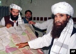 FILE - A 2001 photo of Jalaluddin Haqqani, right, leader of the Haqqani Network, pointing to a map of Afghanistan during a visit to Islamabad, Pakistan while his son Naziruddin, left, looks on.