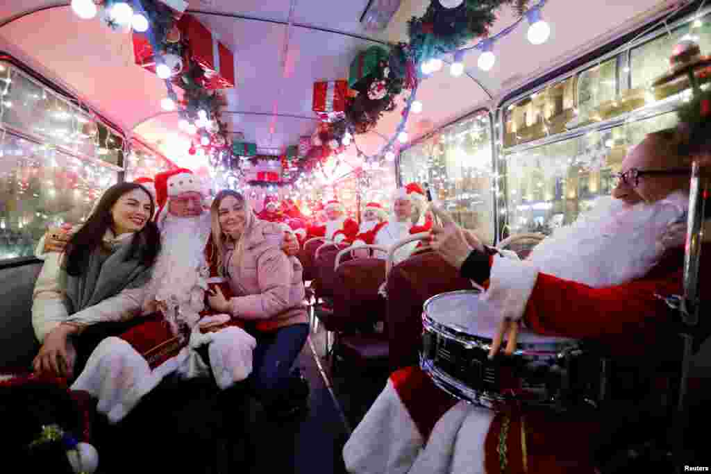 A musician dressed as Santa Claus takes a photo with passengers on a bus decorated for Christmas and New Year celebrations in St. Petersburg, Russia, Dec. 24, 2019.
