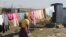 FILE - In this Aug. 12, 2016 photo, a woman heads to an outside pit latrine toilet where she shares a shack housing five people, in Marikana, South Africa. 