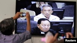 FILE - Journalists take photographs of a television screen showing the trial of Kaing Guek Eav, alias Duch, former chief of the S-21 prison, at the Extraordinary Chambers in the Courts of Cambodia (ECCC) on the outskirts of Phnom Penh, Feb. 3, 2012.