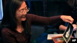 Laurie Yasui picks up photos of her father Minoru Yasui during an interview at her daughters home in Kansas City, Mo., Friday, Nov. 20, 2015.