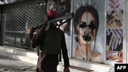Un combatiente talibán pasa frente a un salón de belleza con imágenes de mujeres desfiguradas con pintura en aerosol en Shar-e-Naw en Kabul.
