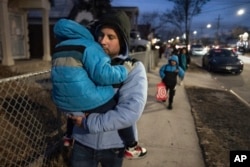 Gabriel Montilla carga a su hijo después de recoger a sus hijos de su escuela en el vecindario Flatbush de Brooklyn y viajar con ellos a un refugio en el vecindario Jamaica del distrito Queens de Nueva York, el martes 14 de enero de 2025.