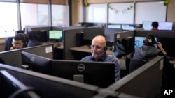 FILE - Customer Experience Representatives Stanley Solis, center, and other representatives take calls at an Alorica center, Monday, Aug. 19, 2024, in San Antonio. (AP Photo/Eric Gay)