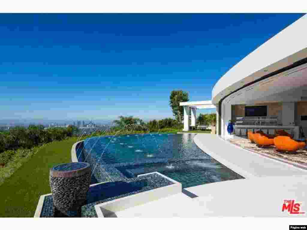 Uma piscina ao ar livre e parede de vidro adornam a casa e permitem que os moradores apreciem a vista.