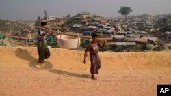 FILE - Rohingya refugees carry a hume pipe in Balukhali refugee camp near Cox's Bazar, in Bangladesh, Nov. 17, 2018. 