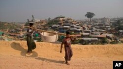 Rohingya refugees carry a hume pipe in Balukhali refugee camp near Cox's Bazar, in Bangladesh, Nov. 17, 2018. 