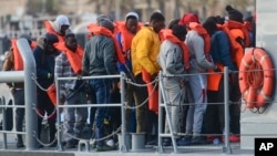 Migrants disembark after being transferred to Maltese army boats at sea and brought to Valletta harbor, Malta, April 13, 2019. Two Maltese soldiers are being questioned in an attack that left one migrant dead and two wounded.