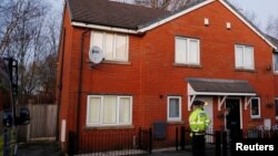 Police officers stand outside a house being searched in connection to a stabbing at Victoria Station in Manchester, Britain, Jan. 1, 2019. 