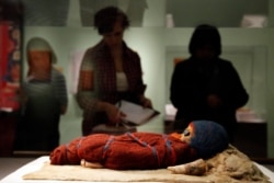 In a Feb. 18, 2011 photo, members of the media view an infant mummy discovered in the Tarim Basin in far western China, at the Secrets of the Silk Road exhibit at the University of Pennsylvania Museum of Archaeology and Anthropology in Philadelphia.