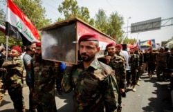 Members of Iraqi Popular Mobilization Forces (PMF) carry the mock coffins of fellow members of PMF, who were killed by U.S. airstrikes on the Syria-Iraq border, during a symbolic funeral in Baghdad, Iraq, June 29, 2021.