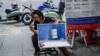 FILE - A vendor selling lottery tickets checks her mobile phone while waiting for customers in Bangkok on March 25, 2019.