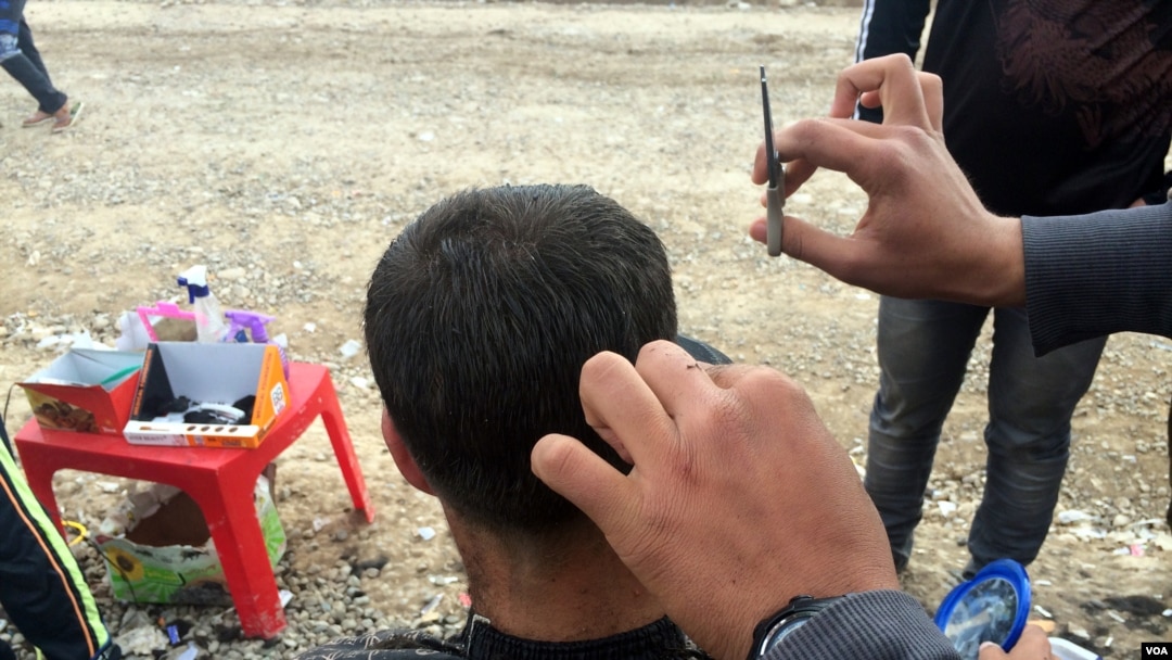 Abdullah sedang memotong rambut seorang pria di kamp Khazir di wilayah Kurdi, Irak (13/12). (VOA/H. Murdock)