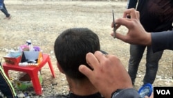 Abdullah sedang memotong rambut seorang pria di kamp Khazir di wilayah Kurdi, Irak (13/12). (VOA/H. Murdock)