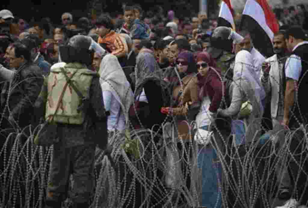 Egyptian anti-Mubarak protesters are seen behind barbed wire as they arrive at Tahrir square in downtown Cairo for more protests, Sunday, Feb. 6, 2011