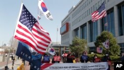 FILE - Demonstrators stage a rally welcoming the visit of U.S. Defense Secretary Lloyd Austin and Secretary of State Antony Blinken outside the Defense Ministry in Seoul, South Korea, March 17, 2021.