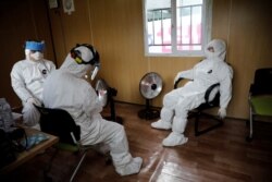 Medical staff in protective gear take a break at a facility of a 'drive-thru' testing center for the novel coronavirus disease of COVID-19 in Yeungnam University Medical Center in Daegu, South Korea, March 3, 2020.