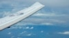 FILE - A U.S. P-8A Poseidon reconnaissance plane flies near Chinese structures and buildings on the man-made Fiery Cross Reef at the Spratlys group of islands in the South China Sea, March 20, 2022.