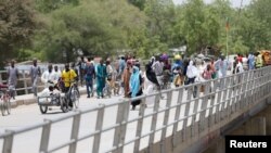 FILE - People cross a bridge linking Cameroon and Nigeria at Gamboru in Borno, Nigeria, April 27, 2017. An improvised explosive device that detonated on the bridge Jan. 6, 2020, killed at least 30 people. 