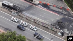 The crash site of a small plane, right, that burned a bus, left, covers an avenue in Sao Paulo, Feb. 7, 2025. 