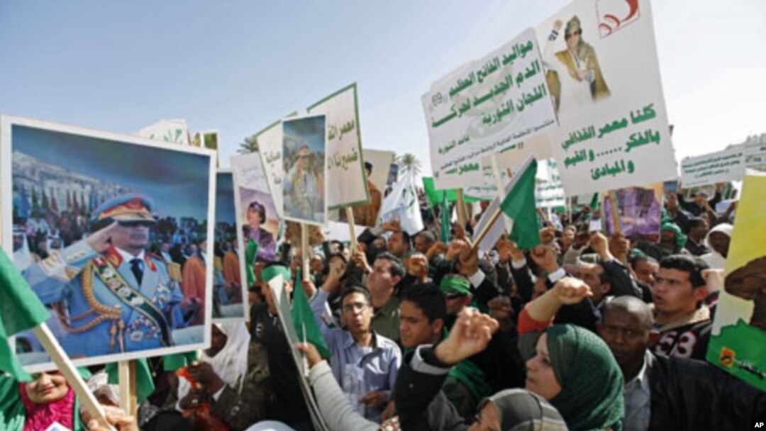 Pro-government supporters hold posters of Libyan leader Muammar Gaddafi as they chant slogans during a demonstration in Tripoli to counteract online calls for an anti-government 'day of rage,' February 17, 2011