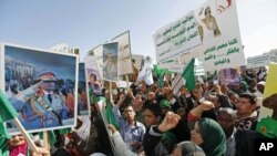 Pro-government supporters hold posters of Libyan leader Muammar Gaddafi as they chant slogans during a demonstration in Tripoli to counteract online calls for an anti-government 'day of rage,' February 17, 2011