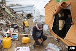 A displaced Palestinian man sits on a plastic jerrycan outside his family tent on a rainy day in Jabalia in the northern Gaza Strip on Feb. 6, 2025, during a truce in the war between Israel and Hamas.