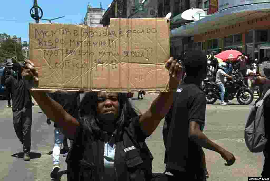 Uma mulher numa manifestação em Maputo segura um cartaz que diz: “Mentir e roubar é um pecado, Bispo Matsinhe!!! A tua Bíblia não diz isso? Levítico 19:11”. 21 novembro 2024