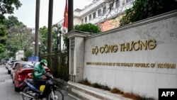 FILE - This photo taken on Feb. 5, 2025 shows a ride-hailing driver using his phone in front of the Ministry of Industry and Trade in Hanoi.