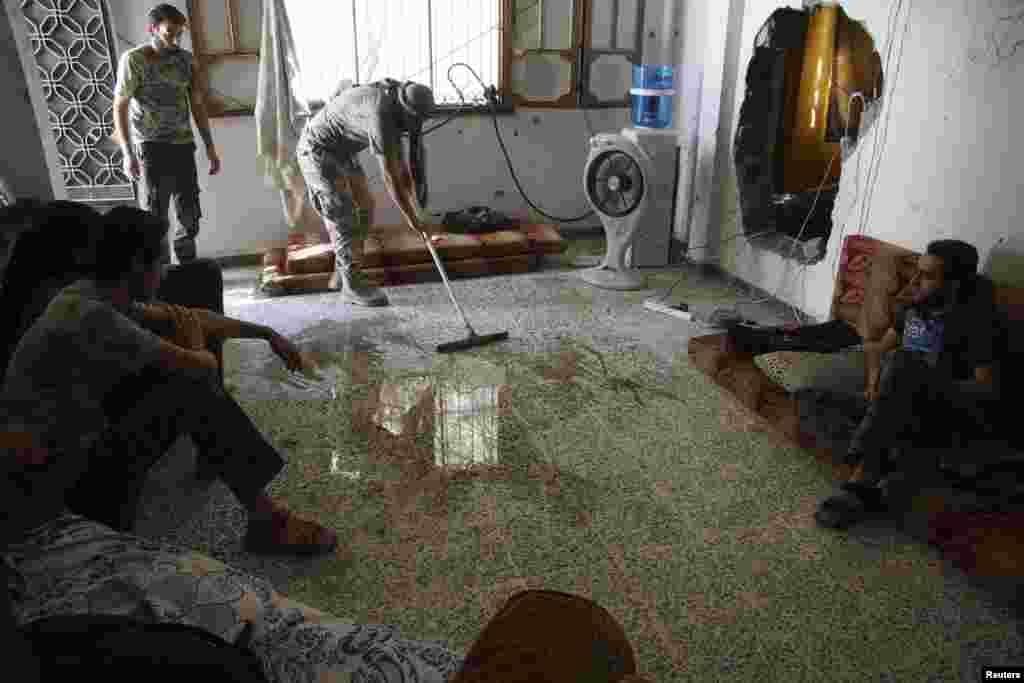 A Free Syrian Army fighter cleans the floor as fellow fighters rest inside a room in Deir al-Zor, July 14, 2013.&nbsp;