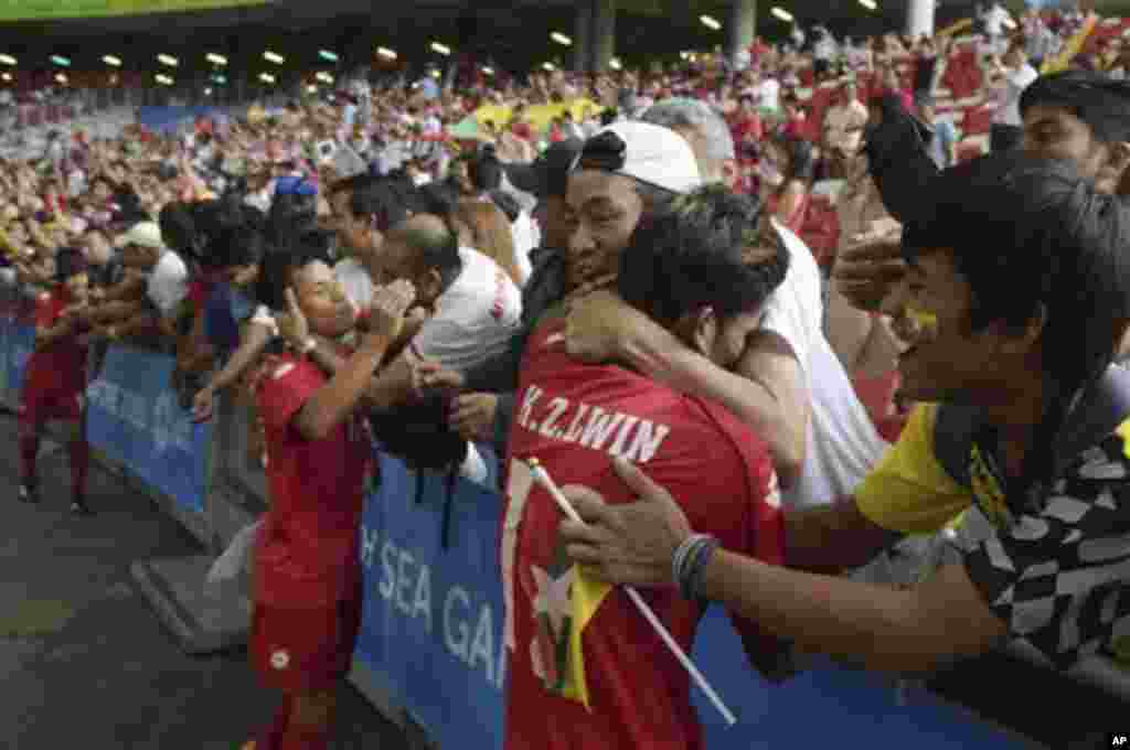 The Myanmar team players are hugged by supporters after winning their game against Vietnam in the soccer semi-final at the SEA Games in Singapore Saturday, June 13, 2015. (AP Photo/Joseph Nair)