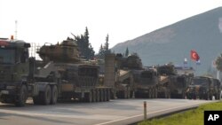 FILE - A convoy of Turkish military trucks carrying tanks and armoured personnel carriers destined for Syria in preparation for a possible military offensive, moves in Hatay province, southeastern Turkey, near the border with Syria, Jan. 14, 2019.
