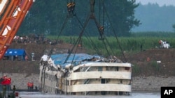 Rescatistas observan cuando el crucero Eastern Star es levantado por grúas del río Yangtze, en la provincia china de Hubei.