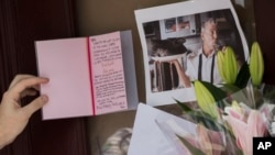 A mourner reads a sympathy card left for Anthony Bourdain at a make shift memorial outside the building that once housed Le Halles restaurant on Park Avenue, Friday, June 8, 2018, in New York.