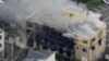 An aerial view shows firefighters battling fires at the site where a man started a fire after spraying a liquid at a three-story studio of Kyoto Animation Co. in Kyoto, western Japan, in this photo taken by Kyodo