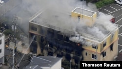 An aerial view shows firefighters battling fires at the site where a man started a fire after spraying a liquid at a three-story studio of Kyoto Animation Co. in Kyoto, western Japan, in this photo taken by Kyodo