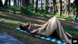 FILE - A migrant man sleeps on the ground at a makeshift migrant camp in Bihac, 450 kilometers northwest of Sarajevo, Bosnia, Aug. 14, 2018. Impoverished Bosnia must race against time to secure proper shelters for thousands of migrants and refugees expected to be stranded in its territory during coming winter. 