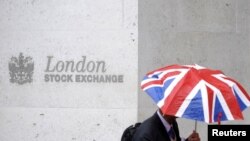 Seorang pekerja berlindung di bawah payung dengan motif bendera Inggris (Union Flag) saat melewati Bursa Efek London di London, Inggris, 1 Oktober 2008. (REUTERS/Toby Melville)