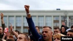 A man raises his fist as he attends an opposition demonstration to protest against presidential election results at the Independence Square in Minsk, Belarus, Aug. 25, 2020. 