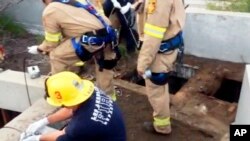 This image from video provided by the Los Angeles Fire Department shows firefighters working where a 13-year-old boy fell through through the small hole at right into a river of sewage in the Griffith Park area of Los Angeles. Jesse Hernandez was swept away Sunday, April 1, 2018, and spent more than 12 hours in the toxic environment of the sewer system before being rescued.