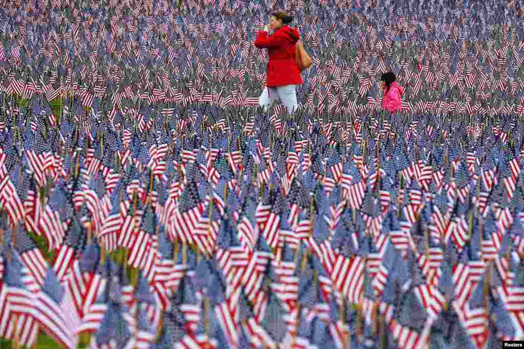 Pedestrians walk through of the field of United States flags displayed by the Massachusetts Military Heroes Fund on the Boston Common in Boston, Massachusetts ahead of the Memorial Day holiday. The 37,000 U.S. flags are planted in memory of every fallen Massachusetts service member from the Revolutionary War to the present.