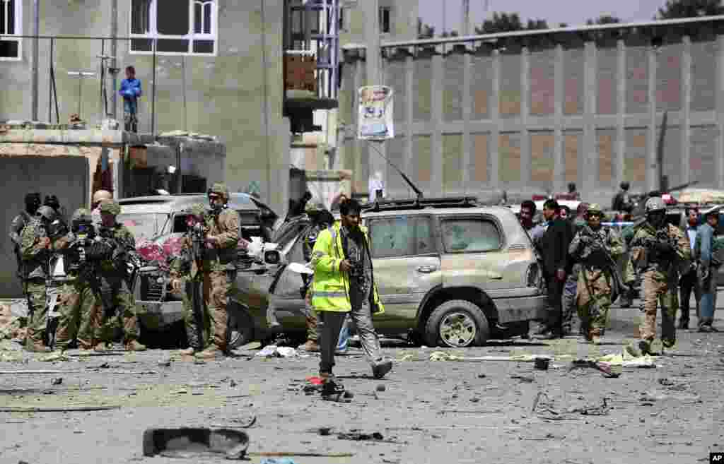 U.S. forces and Afghan security inspect damages at the site of a suicide bombing attack near Kabul's international airport in Kabul, Afghanistan. A suicide bomber detonated an explosives-packed car near the airport, wounding at least 16 civilians.