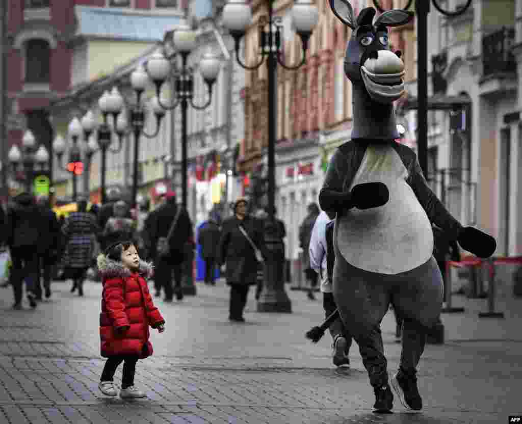 A young girl looks at a person in costume in downtown Moscow, Russia.